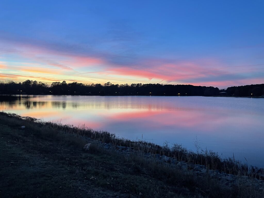 A sky with bright blue, pink and orange colors reflect in a lake below