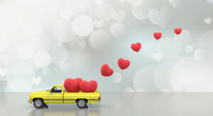 Red hearts are sitting in the bed of a toy yellow truck and also flying out of it